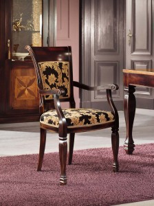 Klasična drvena stolica sa rukonaslonima u boji oraha, sjedište i leđa u tkanini. Može se naručiti u drugim bojama drva i drugim tkaninama.
