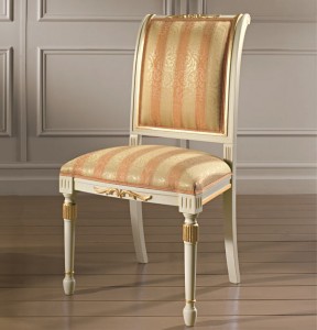 Klasična drvena stolica lakirana u patiniranu bijelu boju sa zlatnim detaljima, sjedište i leđa u tkanini. Može se naručiti u drugim bojama drva i drugim tkaninama.