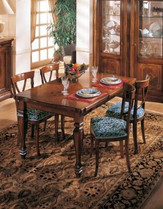 Klasična blagavaona izrađena od masivnog drva u boji oraha. Klasični stol sa pločom u intarziji je veličine 160x100 cm. (otvoreni 240x100). U kompletu je klasična stolica sa sjedištem u tkanini. Može se naručiti u drugim bojama i tkaninama.